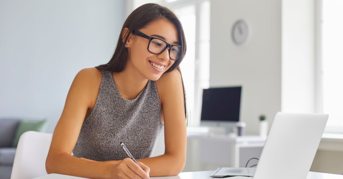 a woman casually smiling and is looking at her laptop