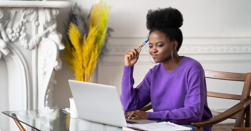 a woman looking at her laptop while thinking