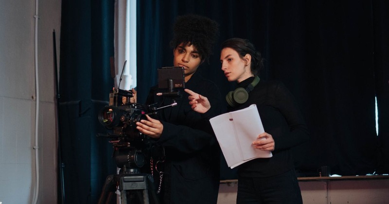 two ladies looking at the camera while holding a script